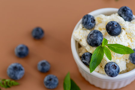 A bowl of cottage cheese decorated with blueberries and aromatic mint leaves.