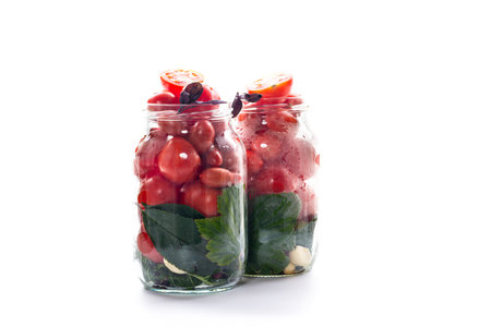 Homemade red tomatoes with herbs in a jar.の写真素材