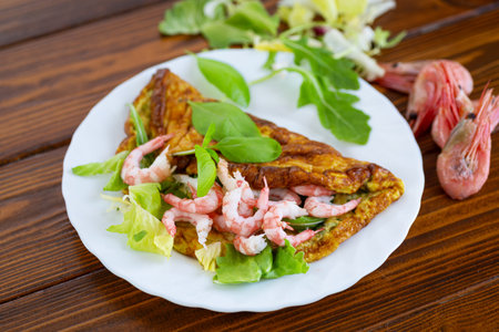 Homemade omelette with seafood on a dark wooden background.