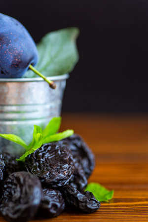 Organic dried prunes with natural plum and green leaves.の写真素材