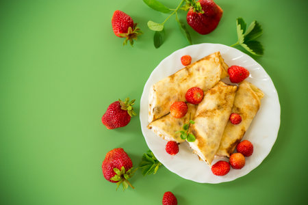 Delicious pancakes with strawberries on a green background.の写真素材