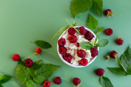 Natural cottage cheese with red raspberries and greens close-up.の写真素材