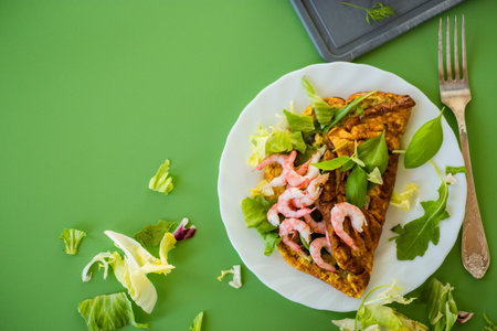 Fried omelette with shrimps and greens on a green background.の写真素材