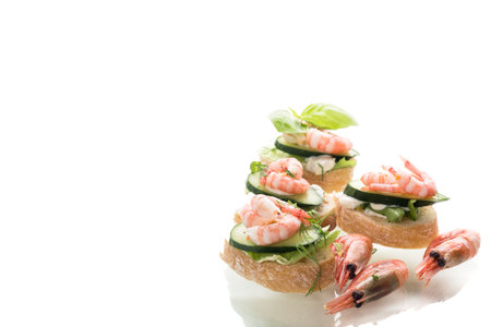 Minimalistic canapes with shrimps, salad and cucumber on a white background.の写真素材