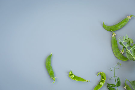 String peas and tops on pastel surface.