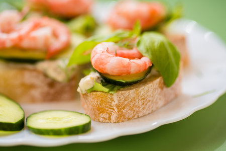 Isolated mini canapes with shrimps, lettuce and cucumber, on a green background.の写真素材