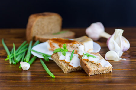 Black bread with lard and onions on a wooden table.の写真素材