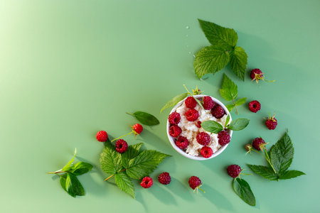 Homemade cottage cheese with raspberries and greens in a cup.
