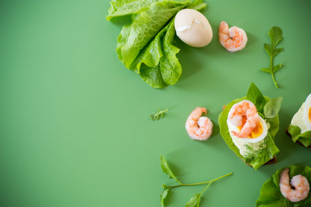 Sandwich with egg and shrimp on green background from above.の写真素材