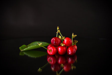 a handful of ripe red cherries on a black background.の写真素材