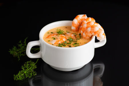 Gourmet seafood soup featuring tender shrimp and aromatic green herbs.の写真素材