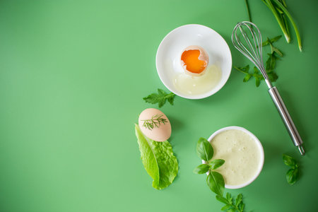 homemade mayonnaise with herbs in a bowl on a green background.