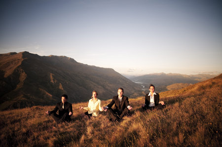 Concept of business people meditating on the mountains.