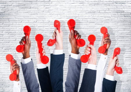 Business people holding red phone.