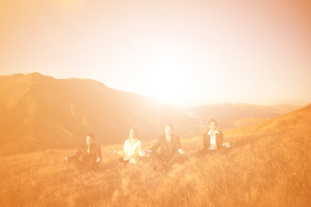 Concept of business people meditating on the mountains.