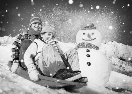 Little Girl and Boy Outdoors Sleding and Snowman Concept