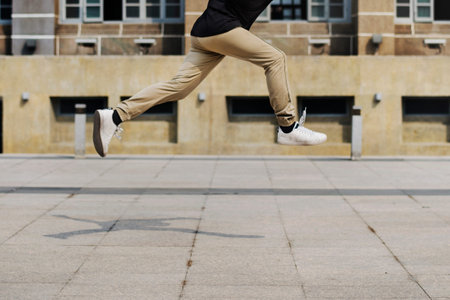 Young man jumping in frount of university campus building