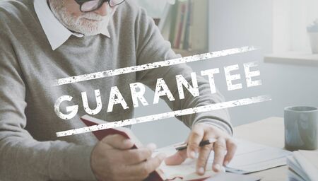 Senior man working on the table with guarantee word