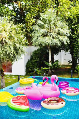 Group of diverse friends enjoying summer time by the pool with inflatable tubes