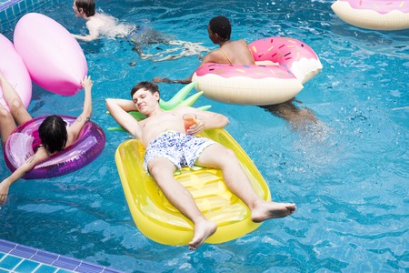 Group of diverse friends enjoying the pool with inflatable tubes