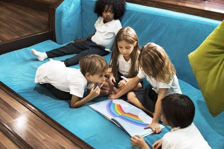 Group of Diverse Young Students Reading Children Story Book Together