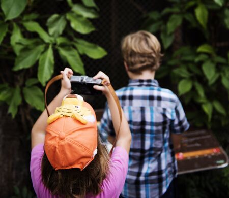 Rear view of young caucasian girl taking photo with camera