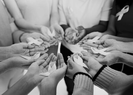 Group of hands holding pink ribbon for breast cancer awareness
