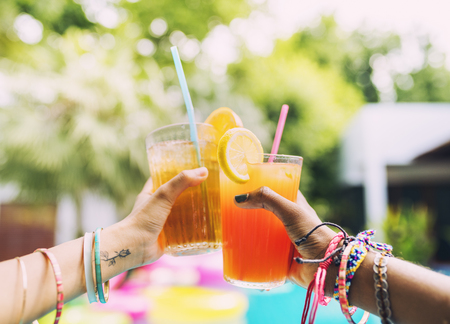 Hands cheers cocktail juice on the pool party