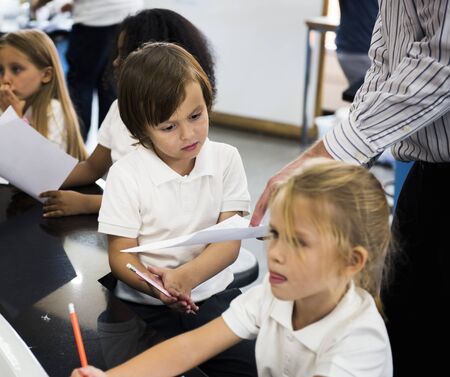 Young kindergarten boy showing his drawing paper with teacher