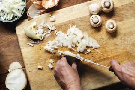 Hands using a knife chopping onion
