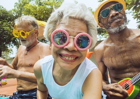 Closeup of diverse senior adults sitting by the pool enjoying summer together