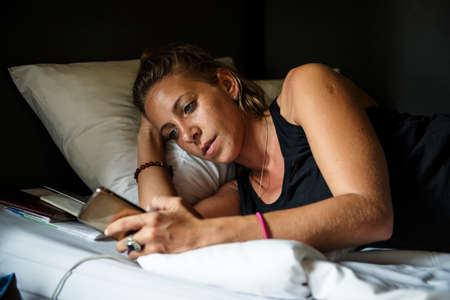 Closeup of caucasian woman lying using mobile phone on bed