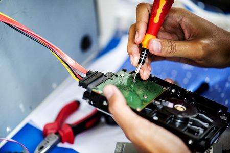 Closeup of hands with screwdriver with computer hard disk
