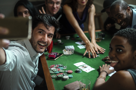 Group of people playing gamble in casino and taking selfie