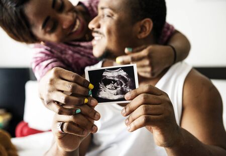 Black couple showing baby ultrasound scan photo