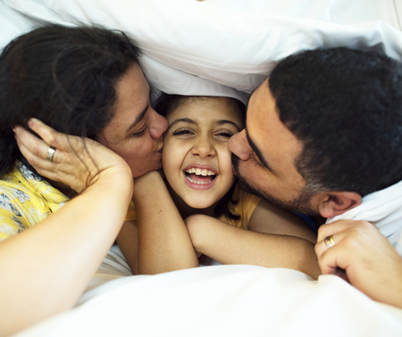 Parents giving daughter kisses on the cheeks