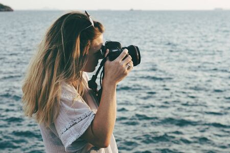 Woman with camera shooting on the beach