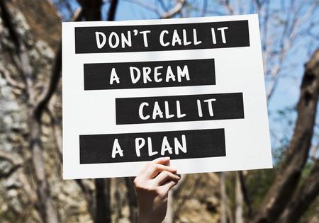 Hand holding don't call it a dream call it a plan placard in the forest