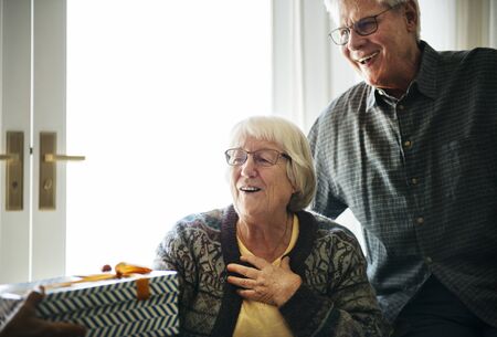 Cheerful senior couple receiving a gift box