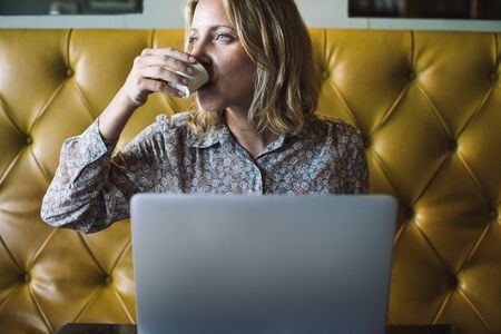Blond woman working on her laptop at a cafe