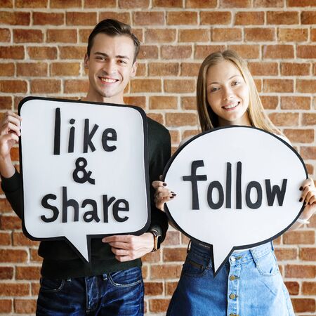 Happy cute young couple holding a thought bubble with social medai concept words