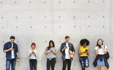 Group of young adults outdoors using smartphones together and chilling