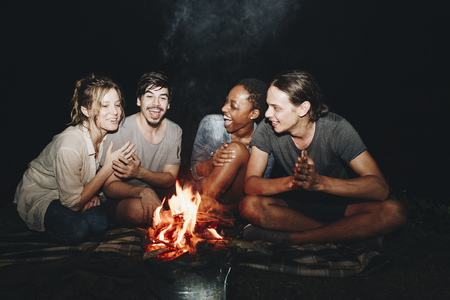 Group of friends sitting around a bonfire at a campsite