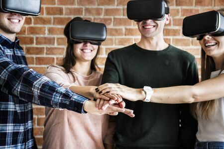 Friends trying on VR headsets and teamwork concept