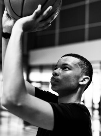 African American teenage boy concentrated on playing basketball