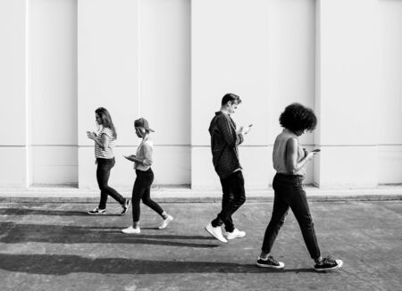 Young adults using smartphones as they are walking outdoors