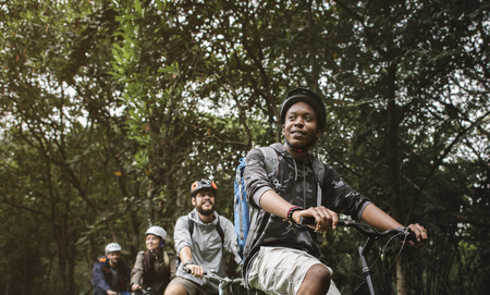 Group of friends ride mountain bike in the forest together