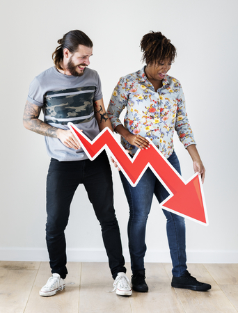 Unhappy interracial couple holding a downward arrow risk and fail concept