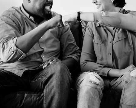 Couple fist bumping each other sitting on couch