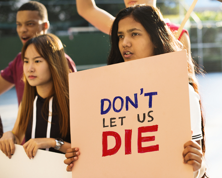 Group of teenagers protesting holding posters saying don't let us die antiwar justice peace...